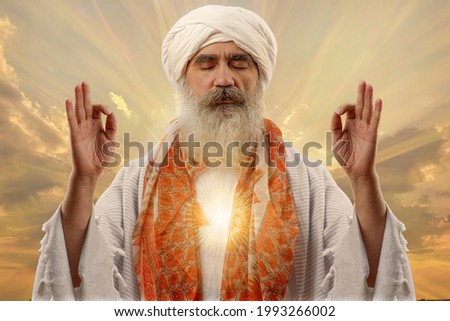 Senior gray-haired beard man in a turban is associated with a Hindu, Jain, Buddhist. Prayer gesture. Meditation siddkhasana yoga opening the Chakras. Royalty-Free Stock Photo #1993266002