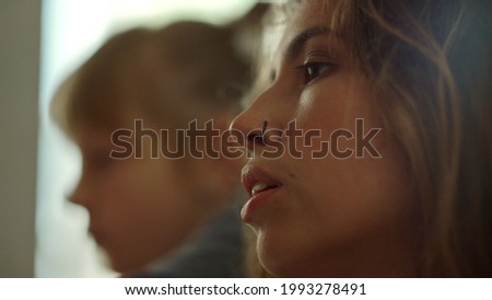 Inspired woman painter biting lip on blurred studio background. Talented girl looking on picture in art studio. Creative female teacher painting with children on art workshop.
