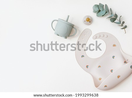 Flat lay Cute baby plate and Silicone bib with on neutral background. Top view, flat lay, baby serving first food Royalty-Free Stock Photo #1993299638