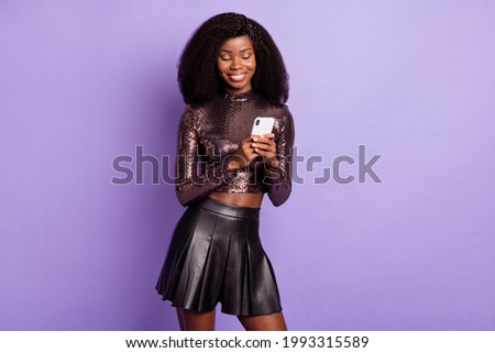 Photo of african lady hold phone look screen wear glossy shirt leather mini skirt isolated purple color background