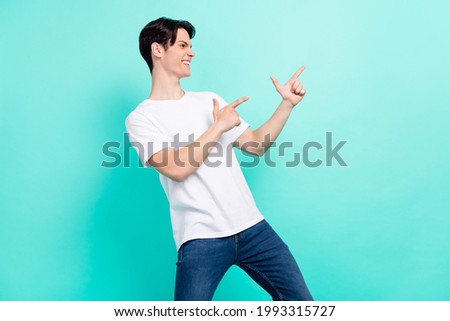 Profile photo of astonished brunet hairdo teen guy point empty space wear white t-shirt isolated on vibrant teal color background