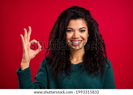 Photo of lucky adorable dark skin woman dressed green pullover smiling showing okey sign isolated red color background