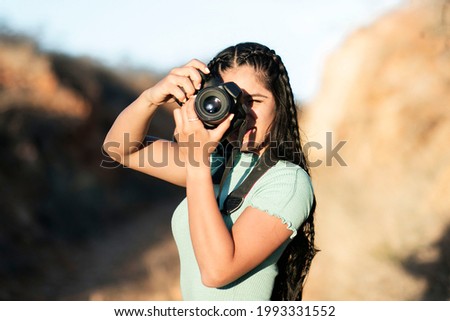 young woman photographer with long black hair taking pictures on a summer sunset