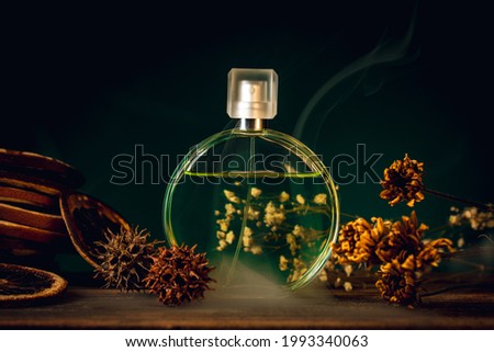Perfume bottle. Parfum for women. Spray glass Bottle with fragrance. Flowers scent. Autumn dried flowers and citrus slices as decoration on natural wooden table. French cosmetics and perfumery.