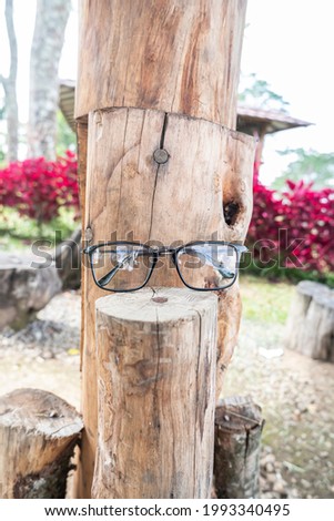 black square eyeglass frame on old wood. square eyeglass frame in the photo from the front with a natural landscape background
