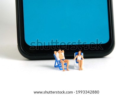 Miniature people toy figure photography. Virtual travel concept, Men and girl relaxing seat at chair above smartphone, isolated on white background. Image photo
