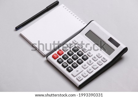 Calculator and notebook on gray background. Top view. Flat lay