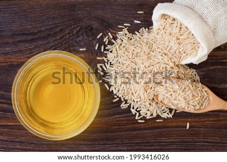 Rice bran oil extract with paddy and brown rice on wood table background. Top view. Flat lay. Royalty-Free Stock Photo #1993416026