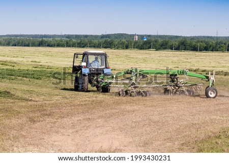 Summer haymaking in the countryside in the field working machinery blue sky
