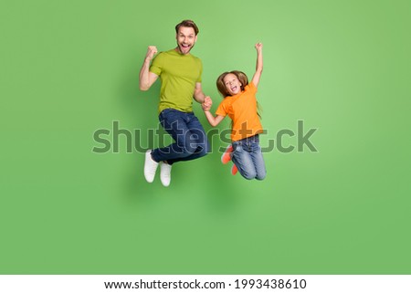 Full length body size view of beautiful trendy cool cheerful people jumping celebrating isolated over green color background