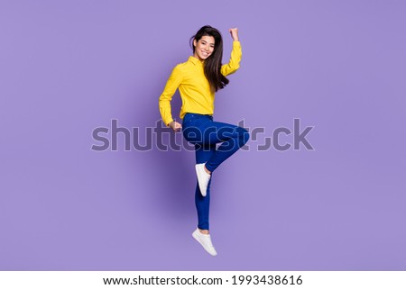 Full body profile side photo of triumphant young woman raise fists win jump up air isolated on violet color background