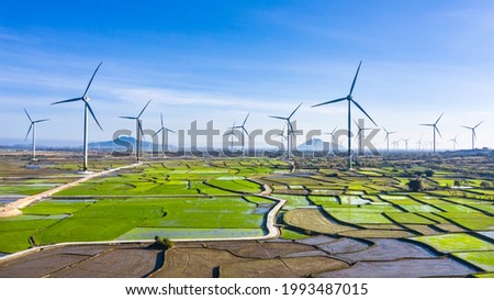 Aerial Drone View of Windmill Energy Farm - Landscape with Turbine Green Energy Production -  Wind turbines Generating Electricity On Green Rice Field