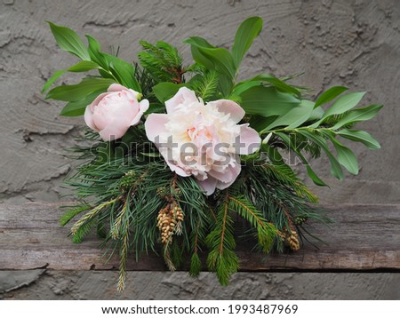 Bouquet with branches of pine, spruce, polygonatum, white peony flowers on a gray background. Spring romantic picture with coniferous plants and flowers for invitation design, greeting card, wallpaper