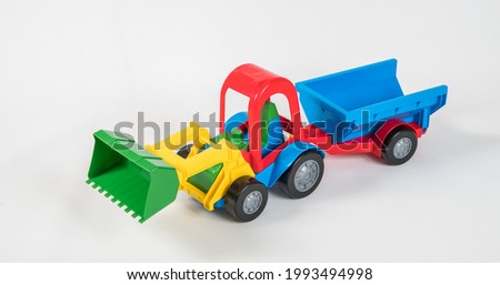 Plastic toy multicolored cars isolated on white background. Grader with a trailer.