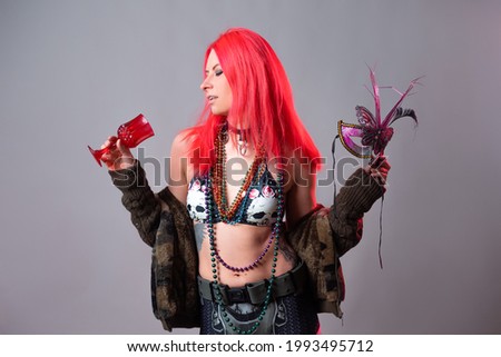 young woman with bright pink hair in a Mardi Gras costume, beads and a mask with feathers, crazy kitsch outfit