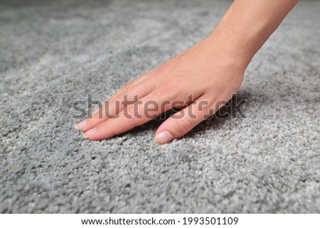 Woman touching grey carpet, close up. Close up of hand touching soft carpet. Gentle and fluffy carpet between fingers. Royalty-Free Stock Photo #1993501109