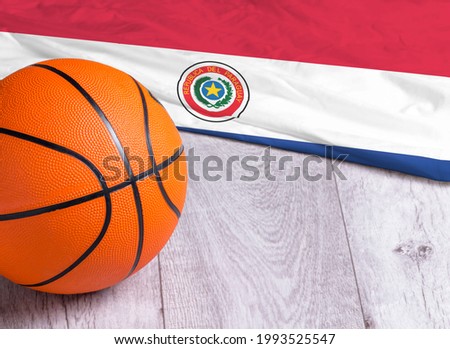 Orange basketball ball with flag Paraguay on wooden parquet. Close-up image of basketball ball over floor in the gym. Basketball championship concept