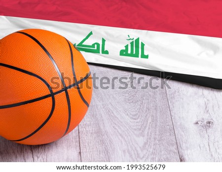 Orange basketball ball with flag Iraq on wooden parquet. Close-up image of basketball ball over floor in the gym. Basketball championship concept