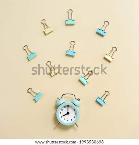 Alarm clock rings and shows 8 oclock in morning, time to go to school concept. Creative Flat lay with clock and paper clips on colored yellow pastel background