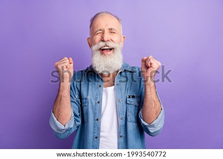 Photo of lucky funny age gentleman wear jeans shirt rising fist smiling isolated violet color background Royalty-Free Stock Photo #1993540772