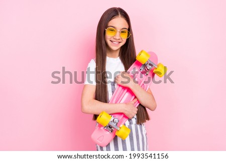 Photo of attractive sportive happy young girl hold hands hug longboard isolated on pastel pink color background