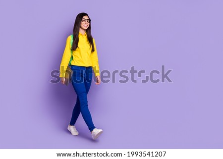 Full length photo of charming young lady look walk empty space wear backpack student isolated on violet color background