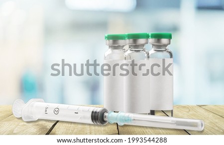Ampoules with COVID-19 coronavirus vaccine, with a syringe for vaccination on the desk.