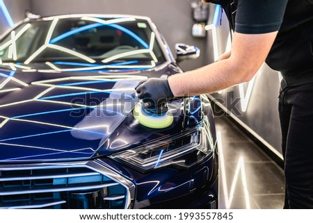 Car detailing - Man with orbital polisher in repair shop polishing car. Selective focus.	 Royalty-Free Stock Photo #1993557845