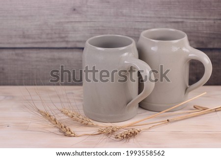 Two beer ceramic mugs with wheat ears on wooden background.German style.Brewing, octoberfest, St.Patrick's day, international beer day concept.copy space for text Royalty-Free Stock Photo #1993558562