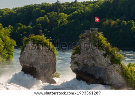 Swiss flag on a rock in the middle of the rhine falls near Schaffhausen in Switzerland 28.5.2021