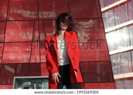 Young woman in a jacket on the background of glass building
