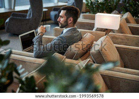 Serious handsome person drinking coffee in the business lounge Royalty-Free Stock Photo #1993569578