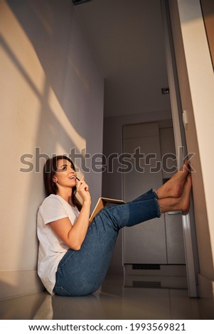 Dreamy brunette raising legs while sitting on floor