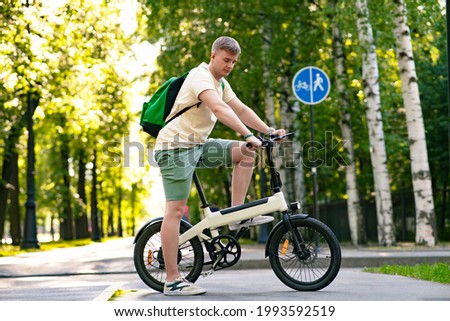 Young guy riding an electric bicycle, bike in a summer park. Active lifestyle, sports Royalty-Free Stock Photo #1993592519