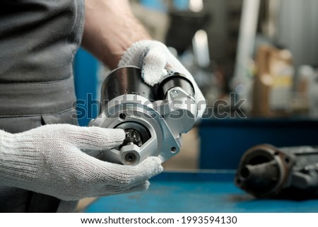 Spare parts.The car starter is in the hands of an auto mechanic.Installing a new and replacing a faulty starter.Maintenance and repair of the car in the service center. Royalty-Free Stock Photo #1993594130