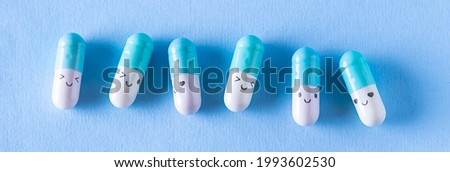 Medical pills with funny faces on light blue background top view. Funny medical banner. Health care concept.