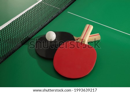 Rackets and ball near net on ping pong table