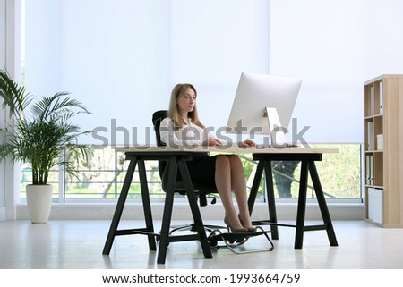 Woman using footrest while working on computer in office Royalty-Free Stock Photo #1993664759