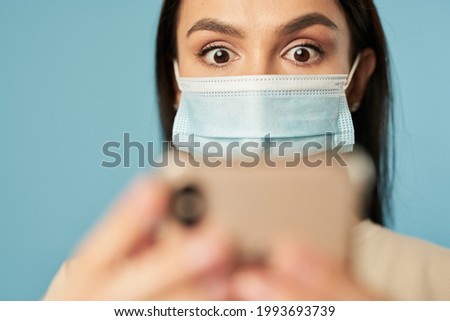Woman in mask using phone and looking at screen in studio