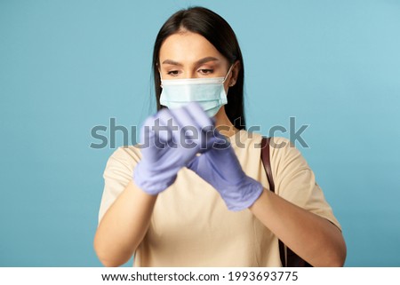 Pretty female wearing blue protective gloves in studio