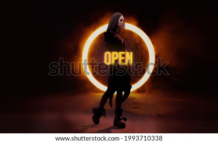 Portrait of mysterious beautiful woman in black futuristic dress on dark background. Neon color geometric circle. Round mystical portal.  