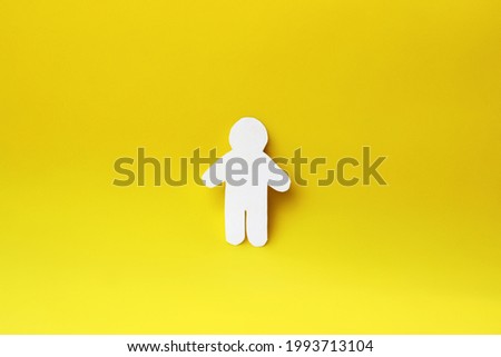 Silhouette of a man of white paper, cut by hand. In the center of the photo on yellow background