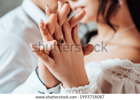 Bride and groom puts a wedding ring on finger. Husband and wife two lovers near window celebrate their wedding engagement. Procreation romantic newlyweds indoor, copy space.