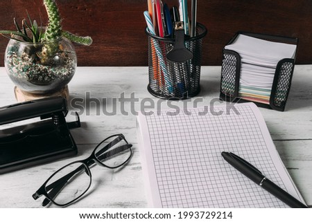 Close-up of a desktop in an office or home office. Office supplies on a wooden table. Glasses, notebook, cactus, pen, hole punch