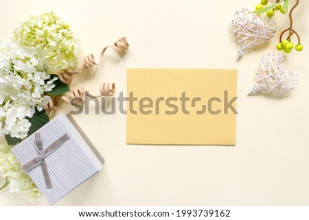 Beautiful bouquet of hydrangeas with gift box on beige background. Greeting card with hearts. Creative background with copy space for text. 

Flat lay, top view concept. 