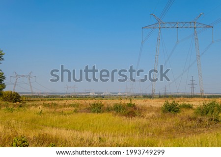 Supporting steel masts of high voltage wires from Kurchatov nuclear power plant. Kurchatov NPP on horizon. Kursk NPP is identical to the damaged Chernobyl NPP built according to a similar design. Royalty-Free Stock Photo #1993749299