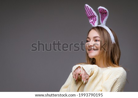 portrait of a cute girl with bunny ears on a gray background