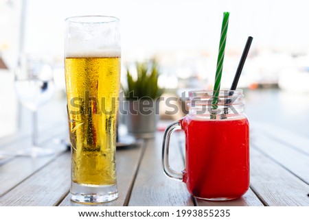 Picture of a cold draught beer and an ice red lemonade on a table