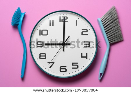 House cleaning product on pink table background, clean time with cleaning tools and clock.