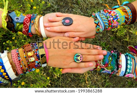 Hippie style friends girls hold hands with handmade bracelets, baubles and rings. Boho fashion                 